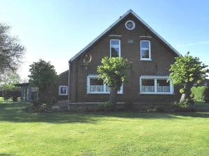 Una casa de ladrillo marrón con árboles en un patio. en Ferienwohnung Nordsee Gulfhof Dornum - mit großem Garten, en Roggenstede