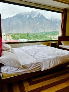 Bett in einem Zimmer mit einem großen Fenster in der Unterkunft Skardu Luxus Hotel in Skardu
