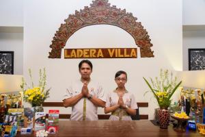 un homme et une femme debout devant une table, les mains devant dans l'établissement Ladera Villa Ubud, à Ubud