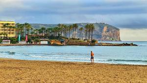 a person walking on a beach with a mountain in the background at Casa El Sueño in Jávea