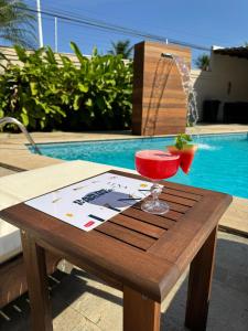 a wooden table with a wine glass on it next to a pool at Luna Hotel Boutique - Beira Mar in Guarujá