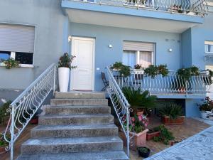 una scala che conduce a una casa blu con piante in vaso di Lellolocations - Casa Osina a San Costanzo 1 altra foto