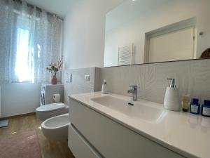 un bagno bianco con lavandino e WC di Lellolocations - Casa Osina a San Costanzo