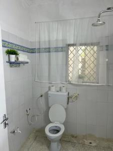 a white bathroom with a toilet and a shower at Tabasamu Gardens in Diani Beach