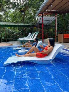 two women laying on a raft in a swimming pool at Cabañas Bambu Mindo in Mindo
