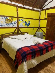 a bedroom with a bed with a plaid blanket at Cabañas Bambu Mindo in Mindo