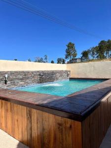 una piscina con una pared de piedra y una valla de madera en Cabaña Campestre Privada Tinita´s Chalet en Taulabé