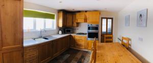 a kitchen with wooden cabinets and a wooden table at Oscar's by the Sea in Bangor