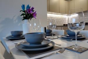 a table with plates and wine glasses on it at Van Gogh Apartment, Bedford - Fast Wifi, Gym & FREE Parking in Bedford