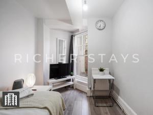 a white bedroom with a bed and a tv on a wall at Hackney Guest Rooms in London