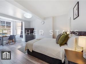 1 dormitorio con 1 cama grande y escritorio en Hackney Guest Rooms en Londres