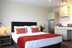 a bedroom with a large bed and a kitchen at Quest Taupo in Taupo