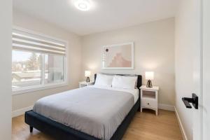 a white bedroom with a bed and a window at Pet Friendly & Accessible, 4 Beds in Calgary