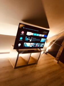 TV de pantalla plana sentada en un stand en una habitación en Le Cottage Suite avec Spa Privatif, 