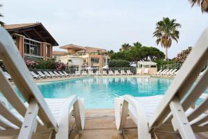 a swimming pool with white chairs and a resort at Résidence Cap Hermes - maeva Home - Appartement 2 pièces 6 personnes - Sé 634 in Fréjus