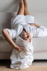 une femme qui se couche sur un canapé enveloppé dans une serviette dans l'établissement Noordzee, Hotel & Spa, à Cadzand-Bad