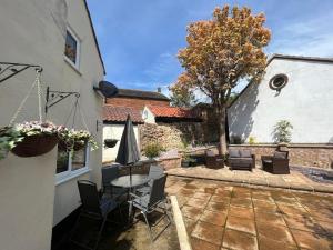 a patio with a table and chairs and an umbrella at 4 Bedroom townhouse on one of the oldest streets in Wymondham