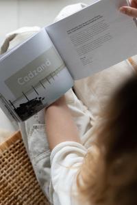 a person is reading a book on a bed at Noordzee, Hotel & Spa in Cadzand-Bad