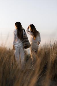 Due donne che camminano in un campo di erba alta di Noordzee, Hotel & Spa a Cadzand-Bad