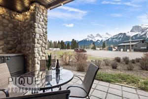 a patio with a table and chairs and mountains at Mountain Haven Retreat, Pool & Hot Tub, UG Parking, Fitness Centre, WiFi! in Canmore