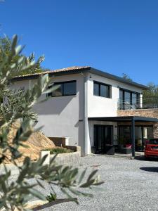 una casa blanca con un coche rojo delante de ella en Villa Contemporaine avec Vue Imprenable en Peyruis