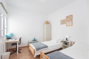 Un dormitorio con dos camas y un escritorio y una mesa. en Piso de 3 habitaciones en Agüimes, en Agüimes