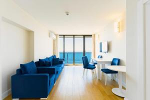 a living room with a blue couch and a table and chairs at Batumi Sea View in Batumi