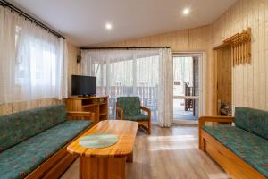 a living room with a couch and a table and a tv at Domki Zacisze, Okoniny in Śliwice