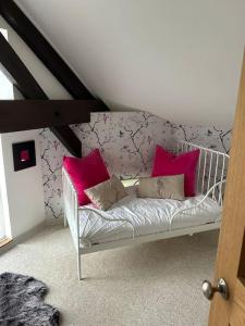 a white crib with pink pillows in a room at Gîte - Saint-Ellier-Du-Maine in Saint-Ellier-du-Maine