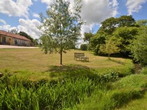 a park bench in a field with a tree at 1 bed in Beaminster 75193 in Mosterton