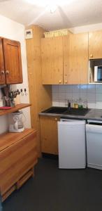 een keuken met houten kasten en een witte koelkast bij Résidence Thabor D - 2 Pièces pour 6 Personnes 28 in Modane