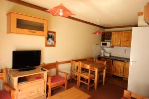 a kitchen and dining room with a table and a television at Chalets Du Thabor - 2 Pièces pour 4 Personnes 82 in Modane