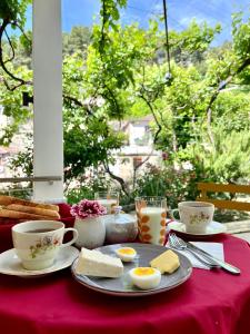 a table with a plate of eggs and bread and cups at Nika's Guest House in Berat