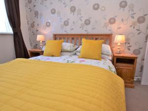 een slaapkamer met een geel bed en 2 nachtkastjes bij 3 Bed in St Day 37014 in Saint Day