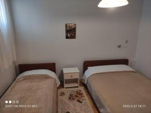 a room with two beds and a table and a clock at Eleni's Rooms in Ioannina