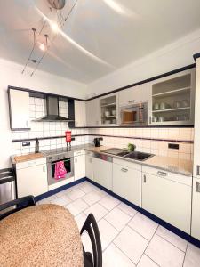 uma cozinha com armários brancos e pisos em azulejo branco em Berchem - Guest House em Bonnevoie