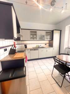uma cozinha com armários brancos e uma mesa e cadeiras em Berchem - Guest House em Bonnevoie