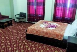 1 dormitorio con cama, silla y cortinas rosas en Swat Inn Hotel en Mingora