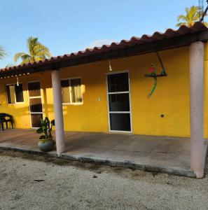 een geel huis met een grote houten veranda bij Villa del Sol in Barra de Potosi