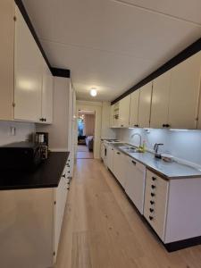 a large kitchen with white cabinets and a wooden floor at Radhus nära sjö, Arlanda och Stockholm in Upplands-Väsby