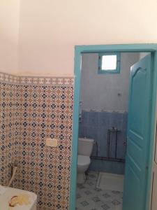 a bathroom with a toilet and a blue door at DAR HIDOUS in Al Māʼīyah