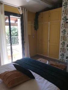 a bedroom with a bed and a large window at chambres dans les Alpilles les jardins de meyrol in Eyguières
