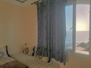 una camera da letto con finestra affacciata sull'oceano di Locals Taghazout surfcamp a Taghazout