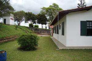 a white building with a grass yard next to a house at Hospedaria Nova Era in Rio Novo