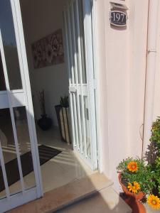 una puerta abierta de una casa con flores y plantas en Sulla via del Mare House, en Terralba