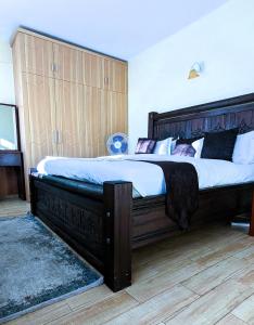 a large bed with a wooden headboard in a bedroom at Tribal Themed 3BR Penthouse in Nairobi