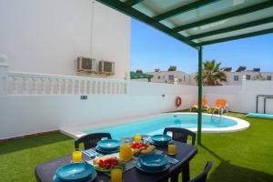 a table with food on it next to a swimming pool at Villa Plata by Villa Plus in Puerto del Carmen