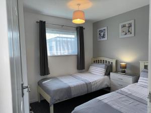 a bedroom with two beds and a window at 62 M&T Chalets , 2 bed detached chalet Florida holiday park Hemsby in Hemsby