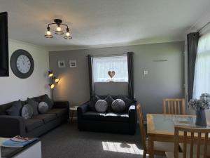 a living room with a couch and a window at 62 M&T Chalets , 2 bed detached chalet Florida holiday park Hemsby in Hemsby +9 photos