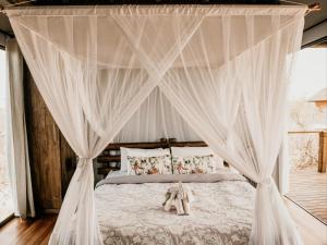 1 dormitorio con cama con dosel y cortinas blancas en Maroelani Lodge- Greater Kruger Private Reserve en Hoedspruit
